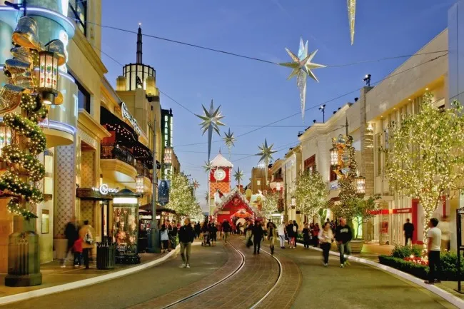 A bustling outdoor shopping street with festive decorations and people walking.