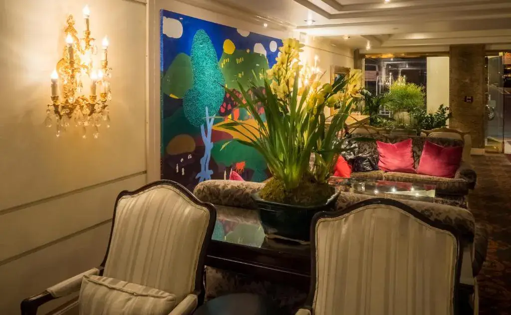 A lobby seating area with a chandelier, sofa, coffee table, armchairs, and artwork.