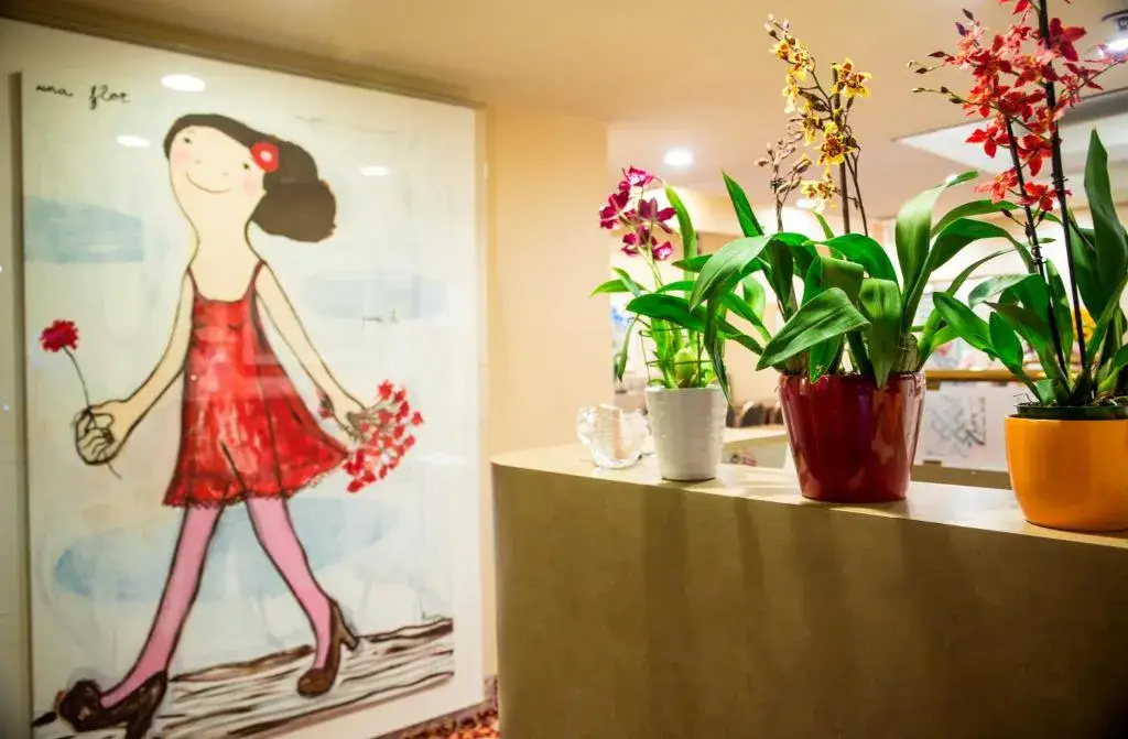A lobby area with a large cartoon-style artwork of a girl in a red dress and potted plants on a shelf.